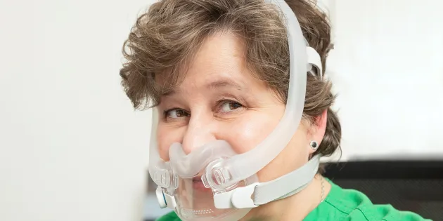 Nainen, jolla on CPAP-maski kasvoillaan. 